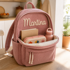 Interior de la mochila de pana abierta con cuaderno, fiambrera y botella